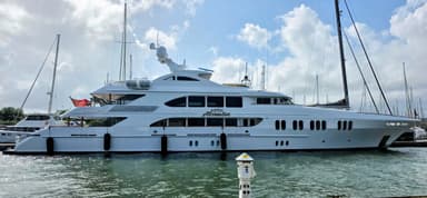 Un yacht blanc amarré dans un port sous un ciel nuageux.