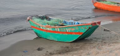 Un bateau coloré sur la plage au bord de l'eau.