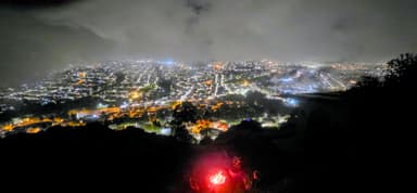 Une vue nocturne d'Amaguaña avec des lumières brillantes et des nuages.