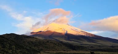 Un volcan majestueux sous un ciel bleu avec des nuages roses.