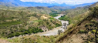 Un paysage verdoyant avec une rivière serpentant à travers les collines en Colombie.