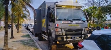 Un camion de voyage garé le long d'une rue à Cartagena, sous des palmiers.