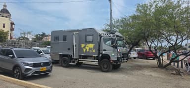 Un camion de voyage garé près d'arbres et de voitures.
