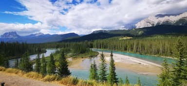 Un paysage naturel avec des rivières et des montagnes sous un ciel bleu.