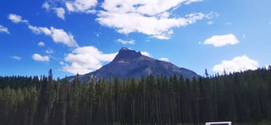 Une montagne majestueuse sous un ciel bleu avec des nuages.