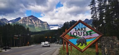 Un panneau indiquant le lac Louise avec des montagnes en arrière-plan.