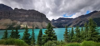 Un lac turquoise entouré de montagnes et d'arbres.