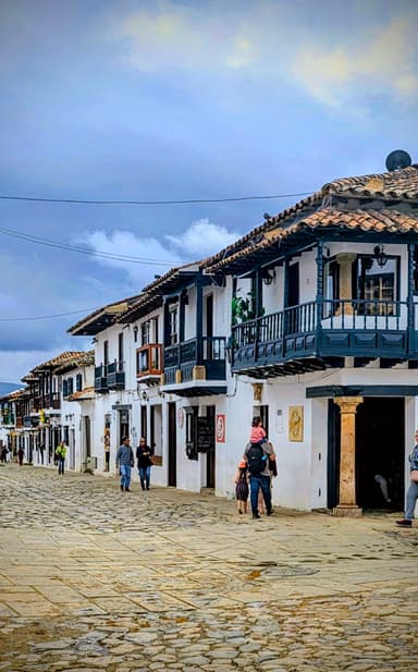 Une rue pavée avec des maisons blanches et des balcons en bois à Ráquira.