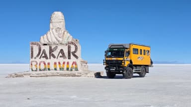Un camion jaune près d'une statue sur le sel blanc de Bolivie.