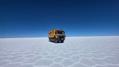 Un véhicule sur le Salar de Uyuni, sous un ciel bleu.