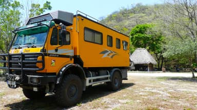 Un camion jaune garé près d'une cabane dans la nature.
