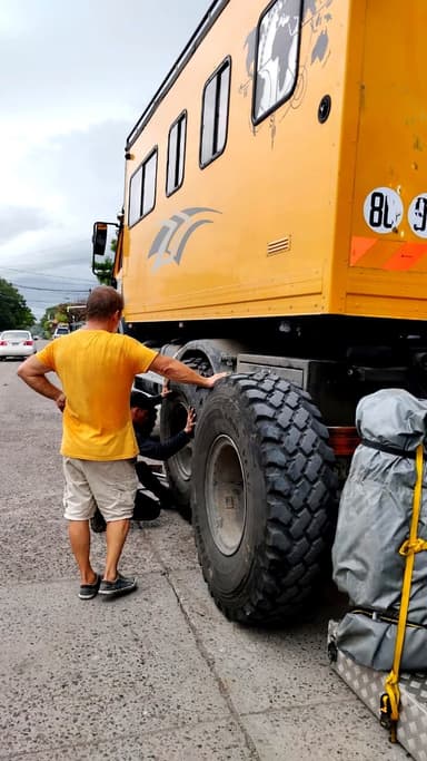 A man inspects a large yellow vehicle on a street in Choluteca.