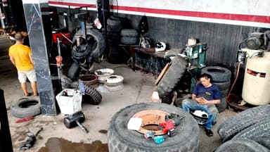 A tire shop with workers and various tires scattered around.