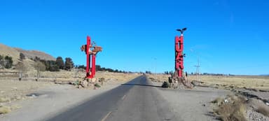 Une route menant à un panneau d'entrée à Huari, sous un ciel bleu.