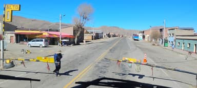 A view of a road with a barrier and buildings under a clear blue sky.