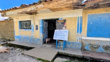 Une maison colorée avec un cochon à l'entrée et un panneau devant.
