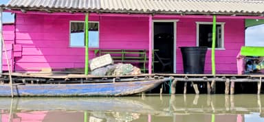 Une maison colorée sur pilotis au bord de l'eau.