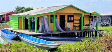 Une maison colorée sur pilotis avec des bateaux au bord de l'eau.
