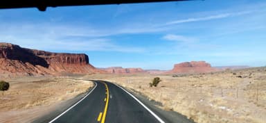 Une route sinueuse à travers des paysages désertiques d'Arizona sous un ciel bleu.