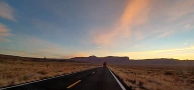 Une route déserte avec des montagnes au coucher du soleil en Arizona.