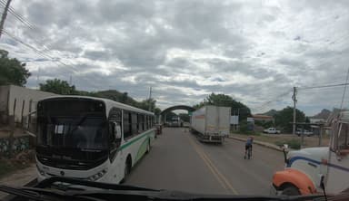 Une rue avec des bus et des camions sous un ciel nuageux.