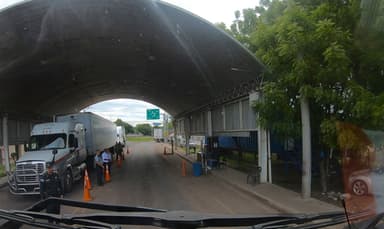 Un passage de contrôle avec des camions et des personnes sous un abri.