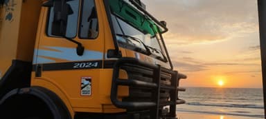 Un camion de collecte des déchets au coucher du soleil sur la plage.