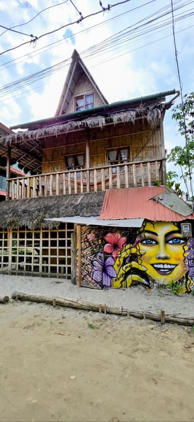 Une maison en bois avec une peinture murale colorée et un ciel nuageux.