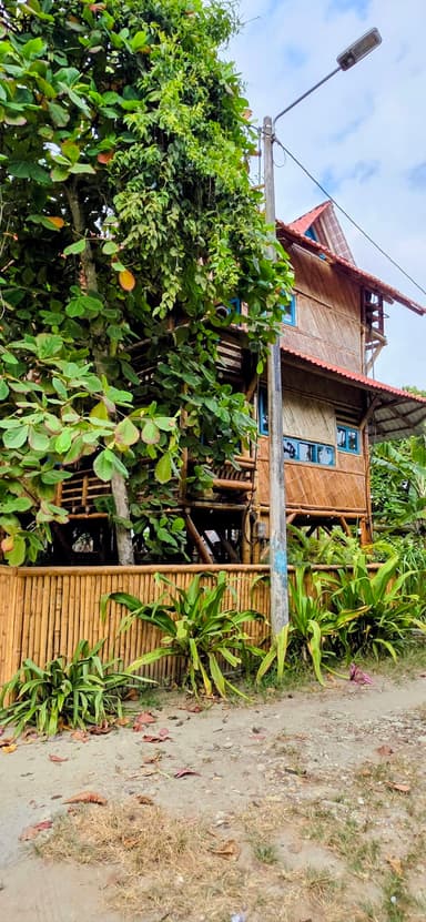 Une maison en bois entourée de verdure sous un ciel nuageux.