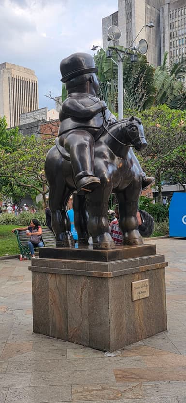Une sculpture en bronze d'un homme sur un cheval dans un parc urbain.