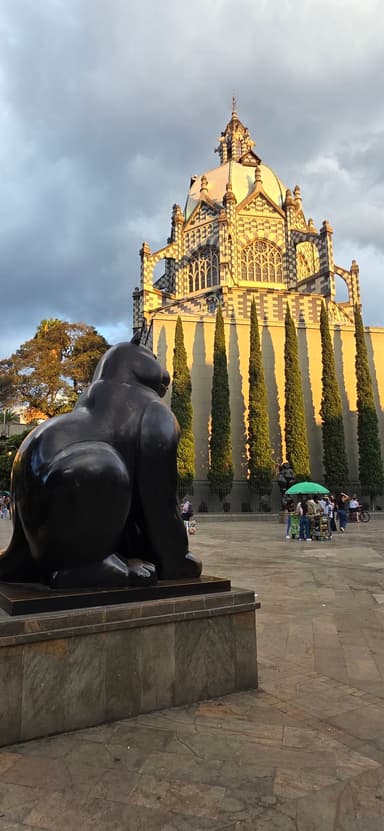 Une statue de gorille devant un bâtiment avec des arbres et un ciel nuageux.