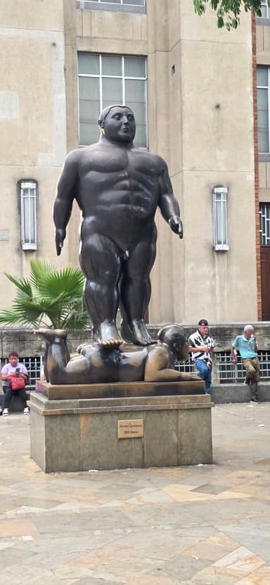 Une statue d'un homme nu en bronze dans un parc.