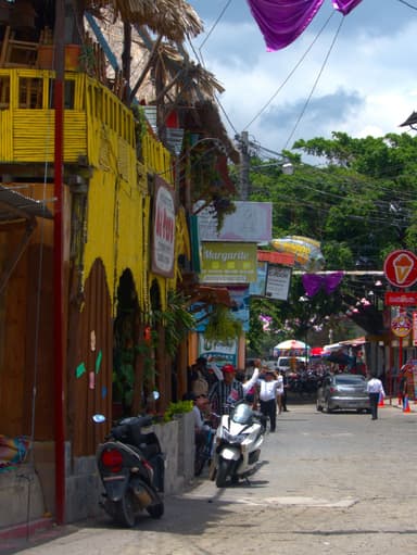 Une rue animée avec des bâtiments colorés et des motos garées.