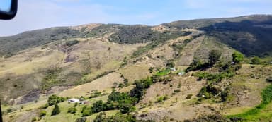 Un paysage montagneux avec des collines verdoyantes et des maisons dispersées.