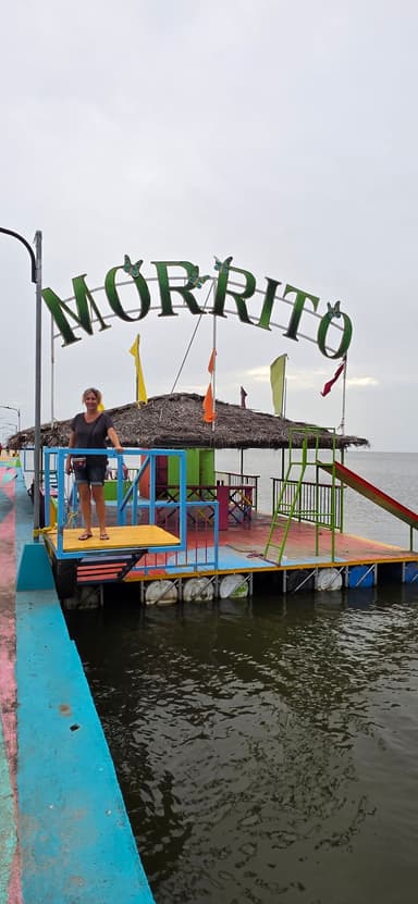 Une femme se tient sur une plateforme colorée au bord de l'eau.
