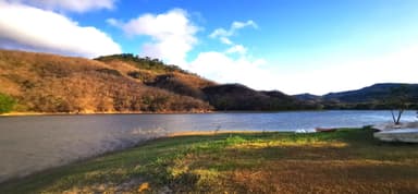 Un paysage naturel avec un lac et des collines sous un ciel bleu.