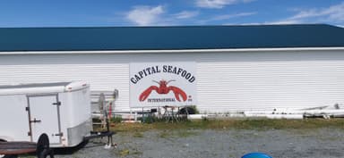 Un bâtiment avec un panneau de fruits de mer sous un ciel bleu.