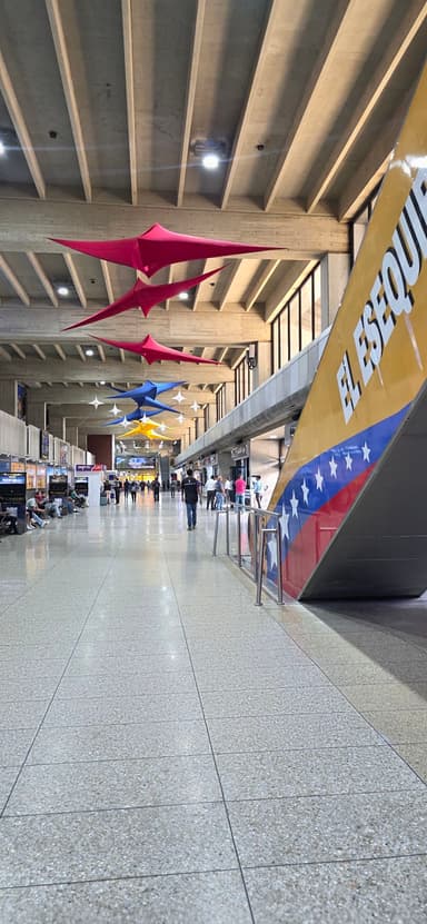 Un hall d'aéroport avec des décorations colorées et des voyageurs.