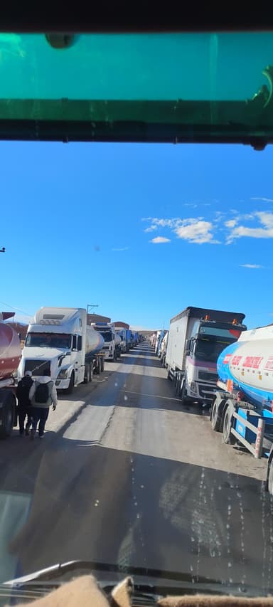 A line of trucks on a road under a clear blue sky.