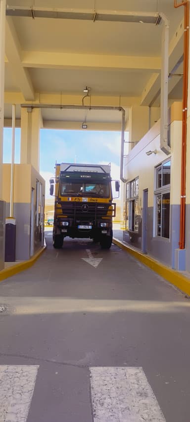 Un camion jaune passe sous un bâtiment dans une zone de contrôle.