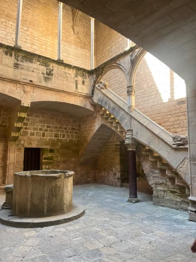 Un intérieur ancien avec un puits et un escalier en pierre.