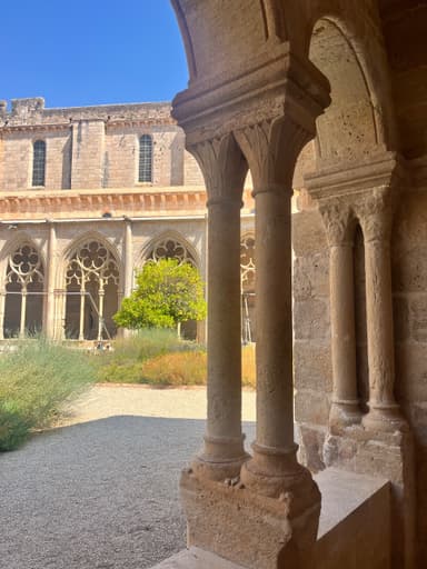 Un jardin avec des colonnes en pierre et un ciel bleu.