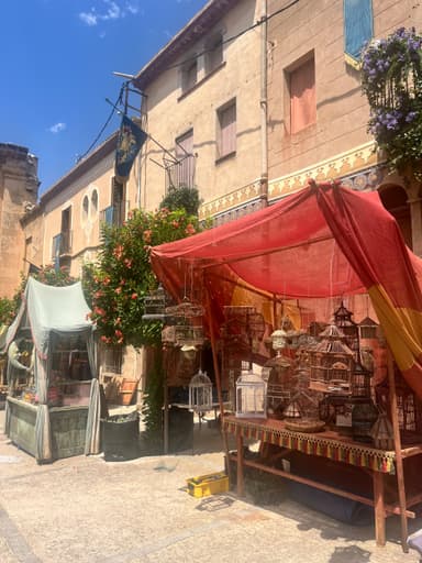 Une rue avec des étals de marché et des bâtiments colorés sous un ciel bleu.
