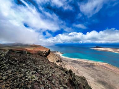 A scenic view of rocky cliffs and turquoise waters under a cloudy sky.