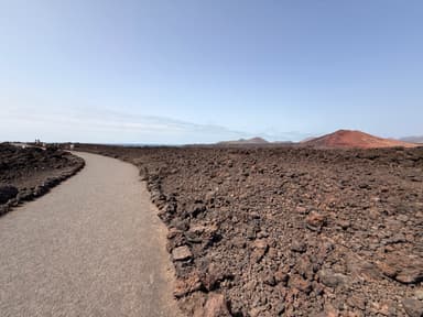 A winding path through volcanic rock landscape under a clear sky.