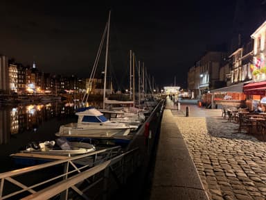 A nighttime view of boats docked along a cobblestone waterfront.