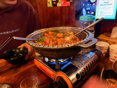 A steaming pot of food on a table in a restaurant.