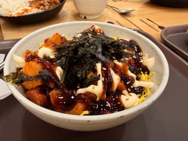 A bowl of food with toppings including seaweed and sauce.
