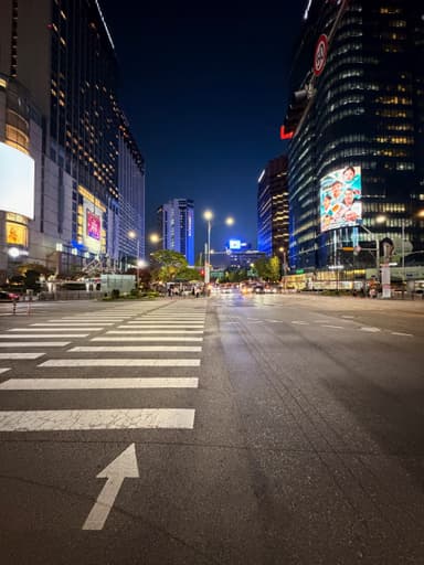 A city street in Seoul at night with bright lights and buildings.