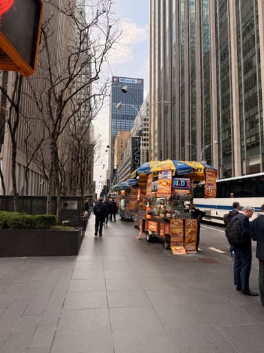 Street vendors with food carts along a busy New York street.
